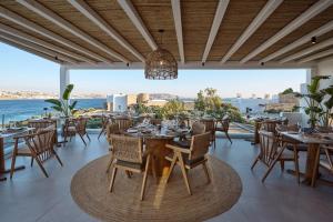 a restaurant with tables and chairs and a view of the ocean at Mykonos Princess Hotel in Agios Stefanos