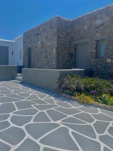 Aegean Hospitality في مدينة ميكونوس: ممشى حجري امام مبنى به ورد