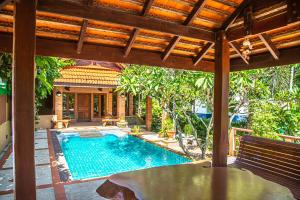 an outdoor swimming pool with a wooden pergola at Kata Pool Villa ​No.7 in Kata Beach