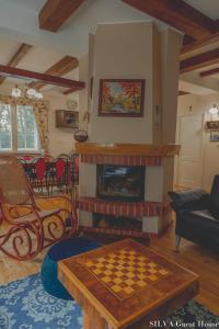 sala de estar con chimenea y tablero de ajedrez en SILVA Guest House - dom wczasowy, tenis, basen, balia i sauna, en Borsk