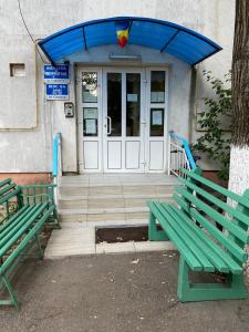 deux bancs verts assis devant une porte dans l'établissement Grove Apartment, à Buzău