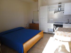 a small bedroom with a blue bed and a kitchen at Acirealevacanze - Romantica Camera sul Mare in Acireale