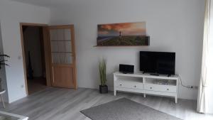 a living room with a television on a white cabinet at Vier Jahreszeiten in Mildstedt