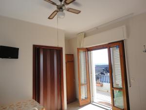 a room with a ceiling fan and a sliding glass door at Acirealevacanze - Romantica Camera sul Mare in Acireale