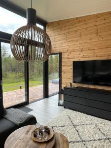 een woonkamer met een grote televisie en een kroonluchter bij Villa JoenPolku Ruka in Ruka