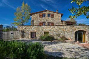 a stone house with a fence in front of it at Borgo Casa al Vento in Gaiole in Chianti