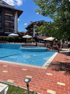 a swimming pool with a brick walkway next to a building at Belvedere- Bansko SPapartments in Bansko