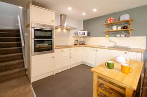 cocina con armarios blancos y mesa de madera en Langdale Retreat en Chapel Stile