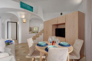 una sala da pranzo con tavolo, sedie e TV di Appartamento Smeralda - SHERDENIA Luxury Apartments a Marinella