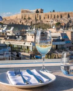 a glass of wine and a plate of food on a table at Niche Hotel Athens in Athens