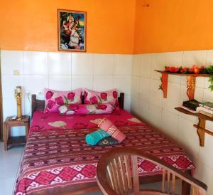a small bedroom with a pink bed with a doll on it at Pelangi Beach Homestay in Amed