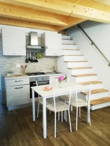 una cocina con una mesa y sillas blancas y una escalera en La casa di Alice en Venecia
