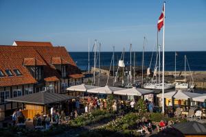 een groep mensen die rond een jachthaven met boten staan bij Hotel Siemsens Gaard in Svaneke