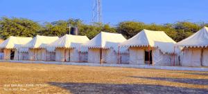 a row of white tents parked in a field at Mahefeel e Rann Resort in Bherandiāla