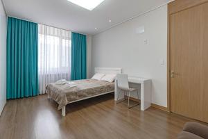 a bedroom with a bed and a desk and a window at Highvill park apart in Astana