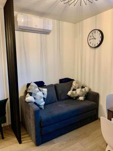 a couch in a living room with a clock on the wall at Eli Apartamentai in Juodkrantė