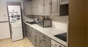 a kitchen with white cabinets and a microwave and a refrigerator at Paradis Du Nord in Wallers
