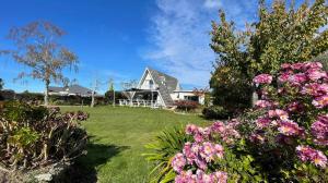 uma casa branca com flores no quintal em Green Tree Haven BnB-Riwaka Tasman Bay em Riwaka