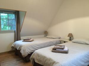 Dos camas individuales en una habitación con ventana. en La Cour Martin à 7 km d'Etretat-Gîte classé 3 étoiles, en Cuverville