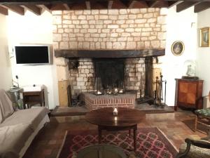 sala de estar con chimenea, sofá y mesa en La Cour Martin à 7 km d'Etretat-Gîte classé 3 étoiles, en Cuverville