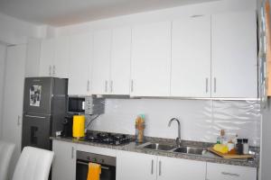 a kitchen with white cabinets and a stainless steel refrigerator at Modern - Luxury Rooftop 2 Bedroom 500 m from Beach in Santa Maria
