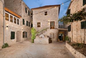 an exterior view of a stone building with a courtyard at Dvor Pitve Villas in Jelsa