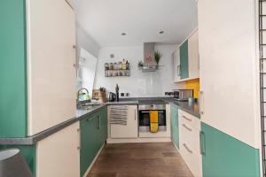 a kitchen with green and white cabinets at GuestReady - Artsy Penthouse in Heart of the City in London