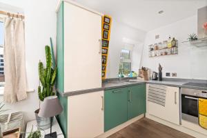 a kitchen with green and white cabinets at GuestReady - Artsy Penthouse in Heart of the City in London