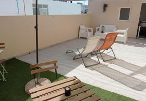 eine Terrasse mit 2 Stühlen, einem Sonnenschirm und einer Bank in der Unterkunft MaBi Paradise Beach House - Arguineguin in Arguineguín