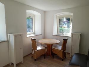 a dining room with a table and chairs and two windows at Haus Guttenberg in Guttenberg