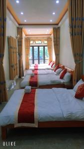 szereg łóżek w pokoju z oknami w obiekcie Nhà nghỉ Nhà Của Lâm - Lam's House Motel w mieście Na Hang