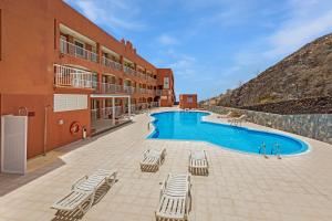 een resort met een zwembad en stoelen en een gebouw bij SMART-Beachview in Costa Calma