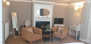a living room with a table and two chairs and a mirror at The Tudor Hotel in Harrow