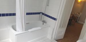 a white bathroom with a tub and a shower at The Tudor Hotel in Harrow