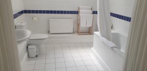 a white bathroom with a toilet and a sink at The Tudor Hotel in Harrow