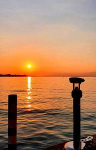 um pôr-do-sol sobre um corpo de água com um poste em Casa RoGi Bardolino Lake em Bardolino
