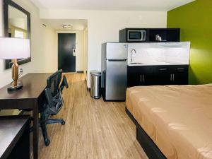 レイクチャールズにあるQuality Inn & Suites Lake Charlesのベッド、デスク、冷蔵庫が備わる客室です。
