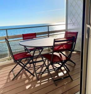 a table and four chairs on a balcony with the ocean at Large studio direct access to the beach in Pornichet