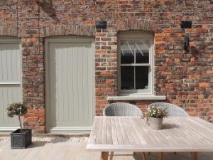 a brick building with doors and a wooden table at Grooms Cottage by Sheriff Hutton Castle near York in Sheriff Hutton