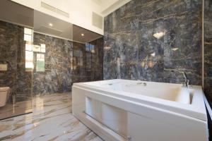 a bathroom with a white tub and black tiles at Modern Revival Luxury Hotel in Thessaloniki