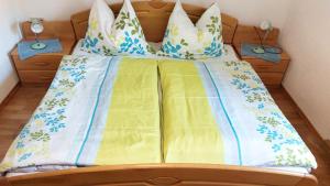 łóżko z żółtą i niebieską pościelą i poduszkami w obiekcie Malerisches Bauernhaus w mieście Lieserhofen