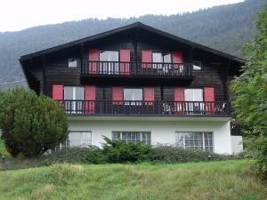 a house with red doors and balconies on a hill at Chalet Esher Surrey in Ried-Brig