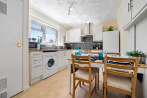 カーディフにあるStay In Cardiff Cathay's Terrace Apartmentの白いキャビネット、テーブルと椅子付きのキッチンが備わります。