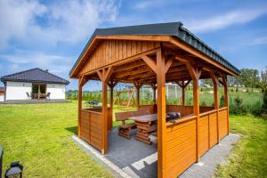 a wooden gazebo with a picnic table in a field at Nadmorskie Zacisze in Dębina