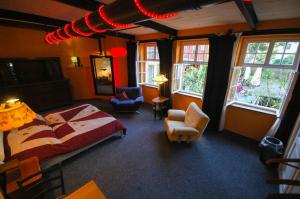 a bedroom with a bed and chairs and windows at Sandino Hostel - Solo Traveler Sanctuary in Berlin