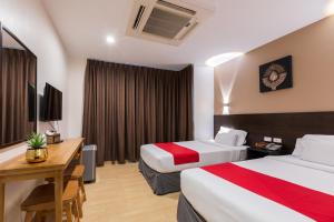a hotel room with two beds and a desk at 24@Home Hotel in Nonthaburi