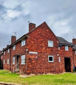 een oud bakstenen gebouw met een deur aan de voorkant bij Sheffield serviced apartment in Greenhill