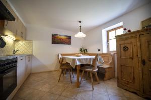 eine Küche mit einem Tisch und Stühlen sowie einem Fenster in der Unterkunft Schoenau Bio & SPA Family Apartments in St. Ulrich in Gröden