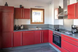 kuchnia z czerwonymi szafkami i zlewem w obiekcie Apartment Les Alpages w mieście Les Gets +3 zdjęcia