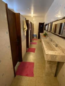 uma casa de banho com uma fila de lavatórios e tapetes vermelhos em Pousada Irmãs Franciscanas em Lages